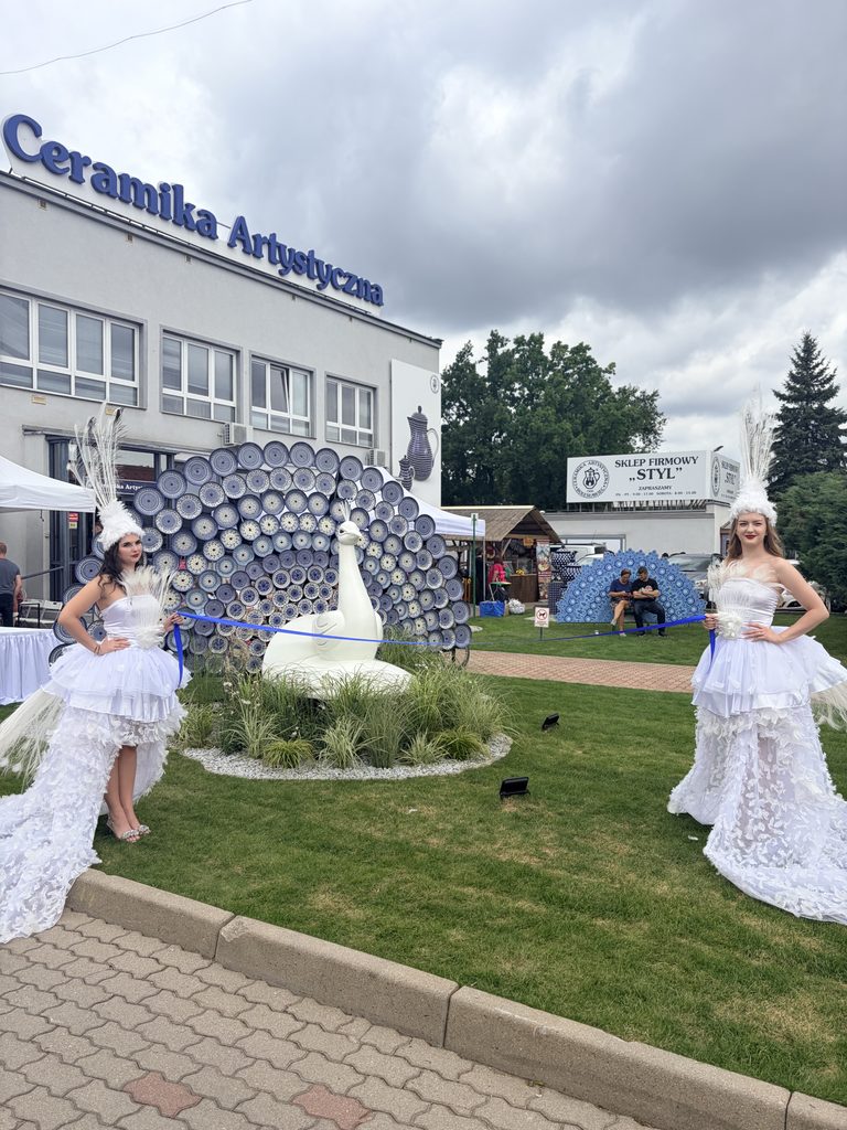 Dwie performerki w białych kostiumach podczas odsłonięcia instalacji pawia